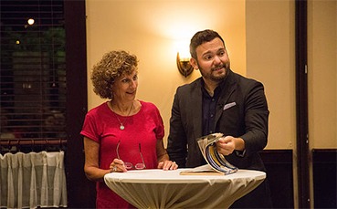 A man and woman standing at a table holding a book, corporate event mentalist.