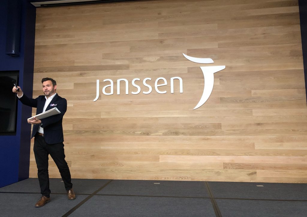 A man standing in front of a corporate event sign.