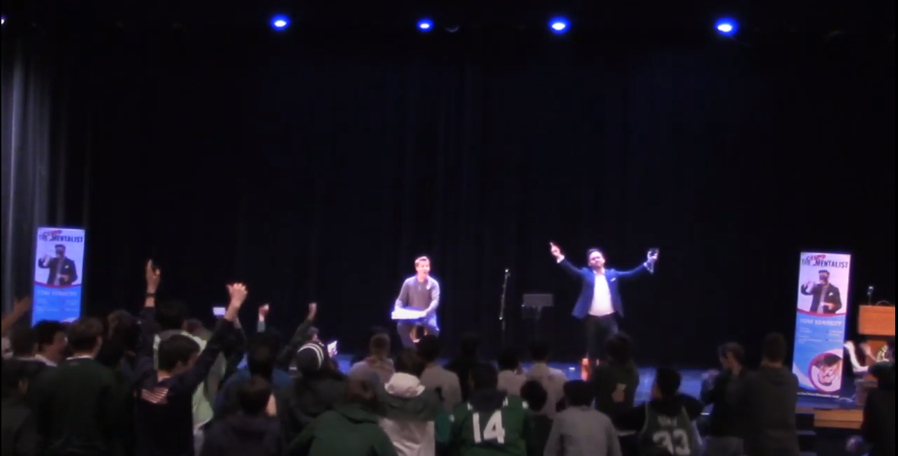 A group of people on stage with their hands raised during a corporate event.